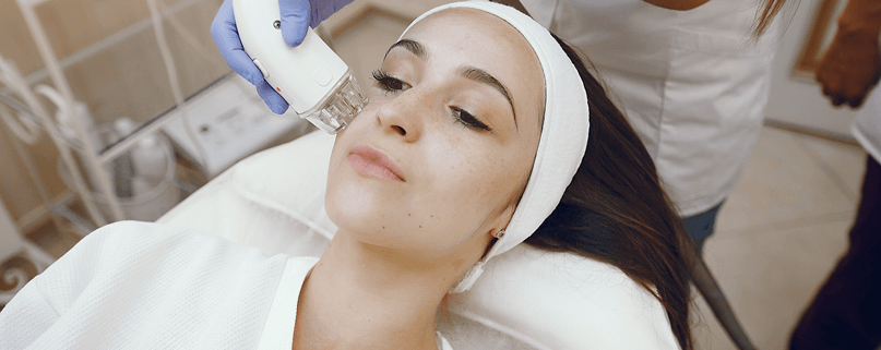 Fractional non-ablative laser treatment being performed on a woman’s face in a professional skin clinic