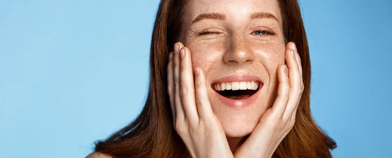 Woman gently touching her cheek, illustrating healthy and rejuvenated skin