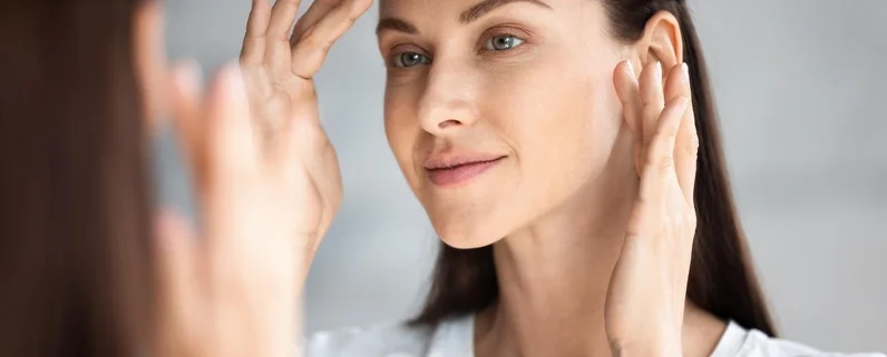 Woman gently touching her cheek with healthy-looking skin